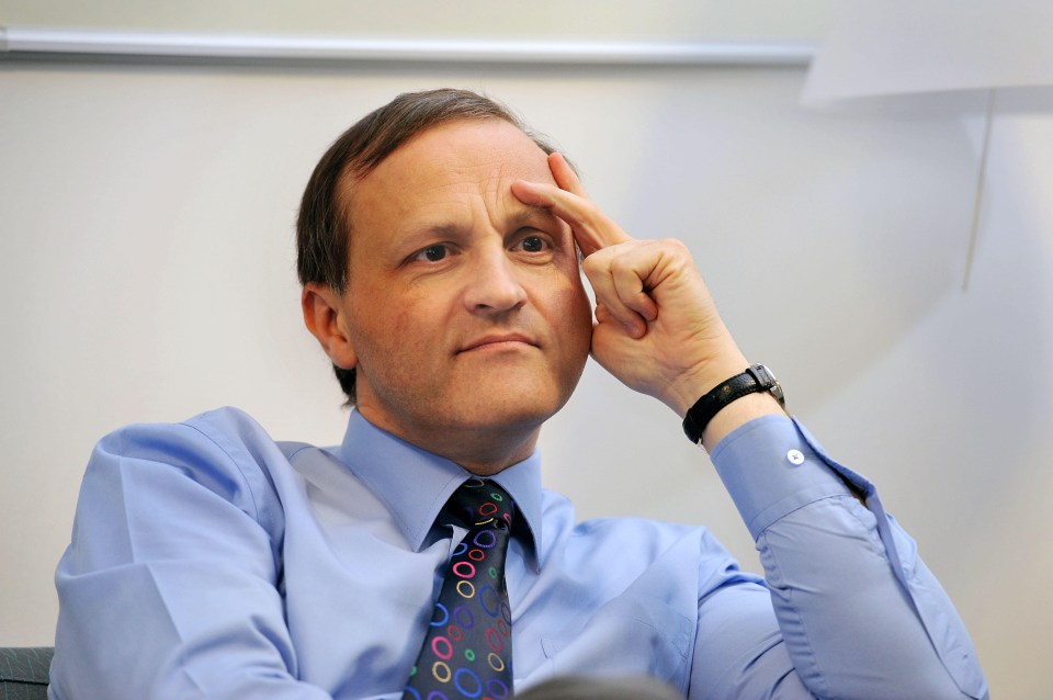 a man in a blue shirt and tie holds his finger to his forehead