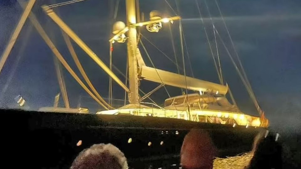 a large sailboat is docked in the water at night .