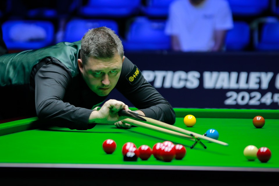 a man playing pool in front of a sign that says optics valley