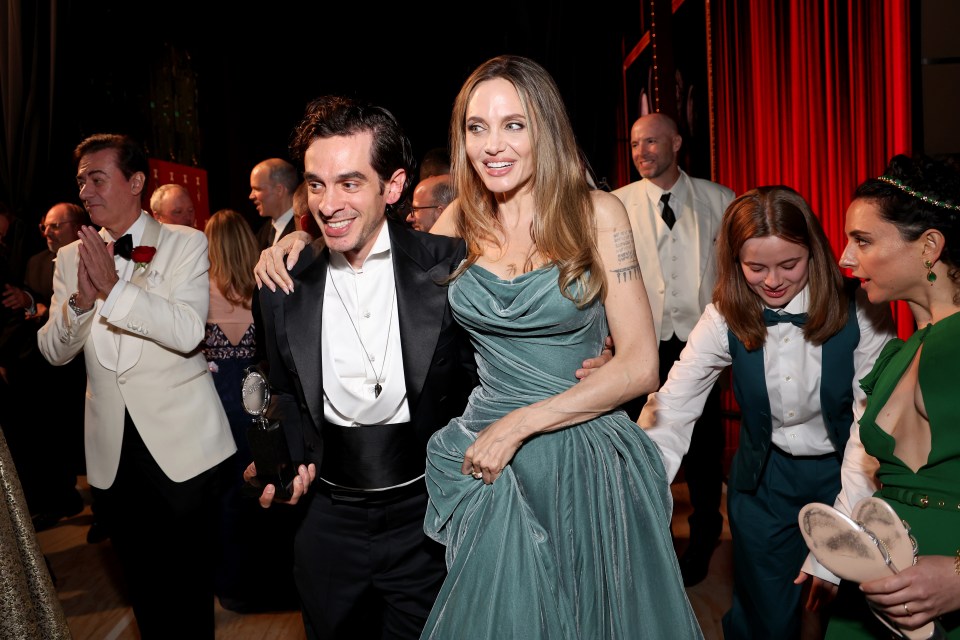 a woman in a green dress stands next to a man in a tuxedo