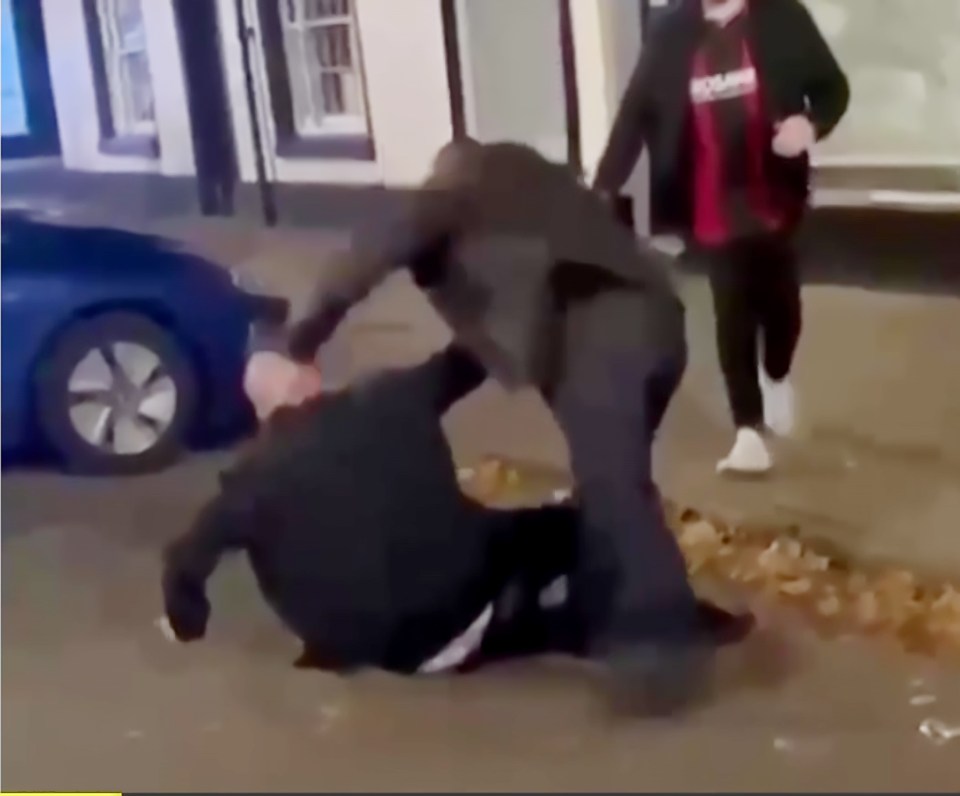 a man is laying on the ground while two other men are standing around him .