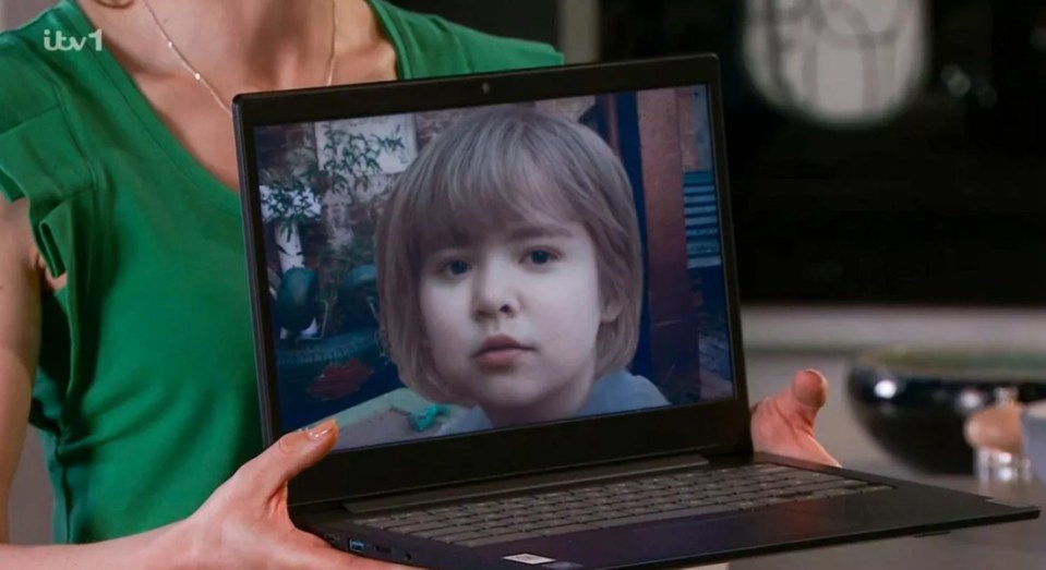 a woman is holding a laptop with a picture of a child on the screen