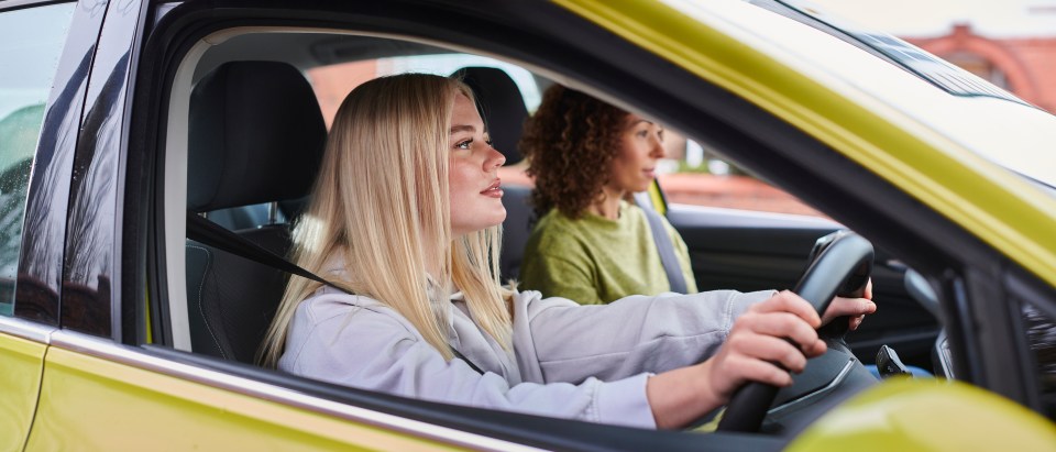 two women are sitting in a car and one is wearing a seat belt