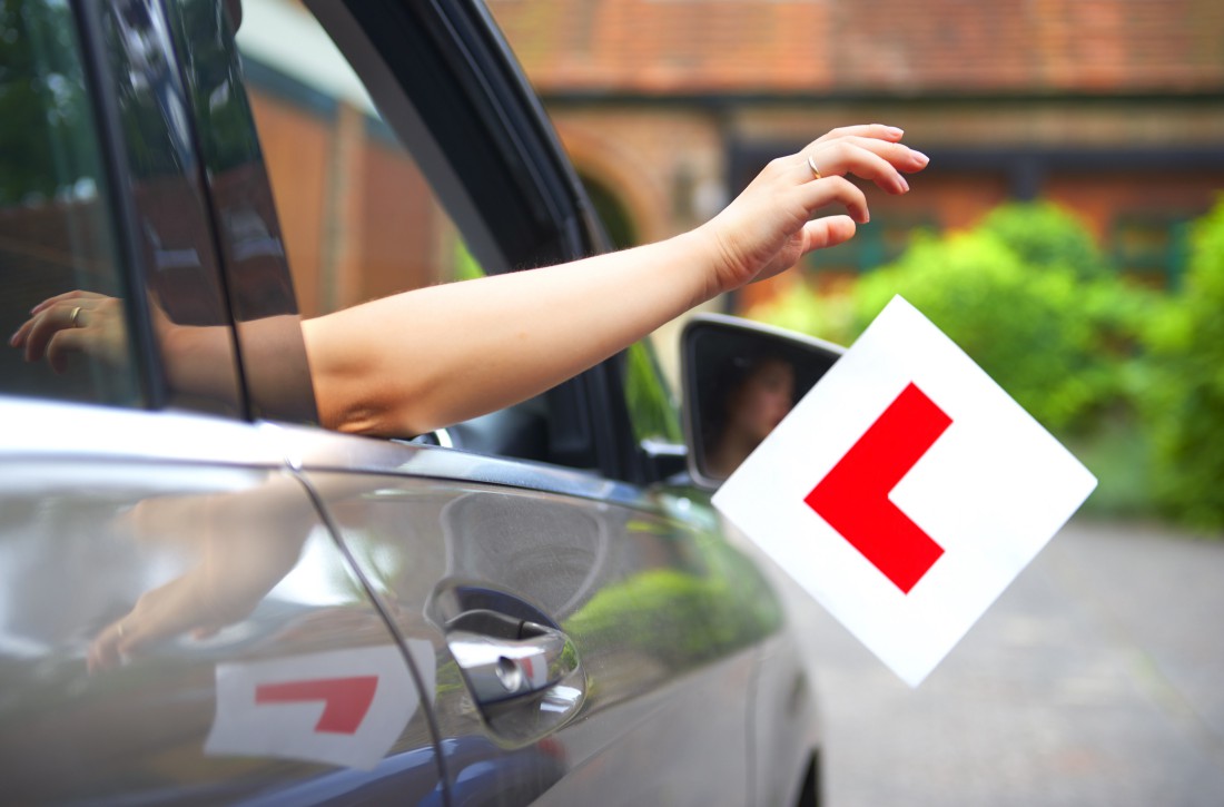 a person in a car holds up a sign that says l on it