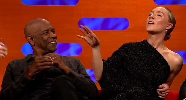 a man and a woman are sitting next to each other on a couch and laughing .