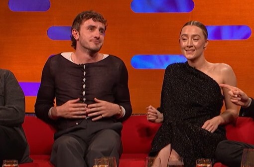 a man and a woman are sitting next to each other on a red couch .