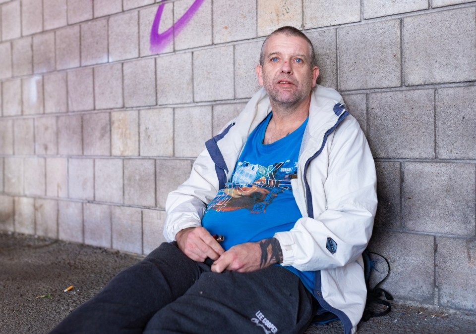 a man sitting on the ground wearing a blue shirt that says ' storm trooper ' on it