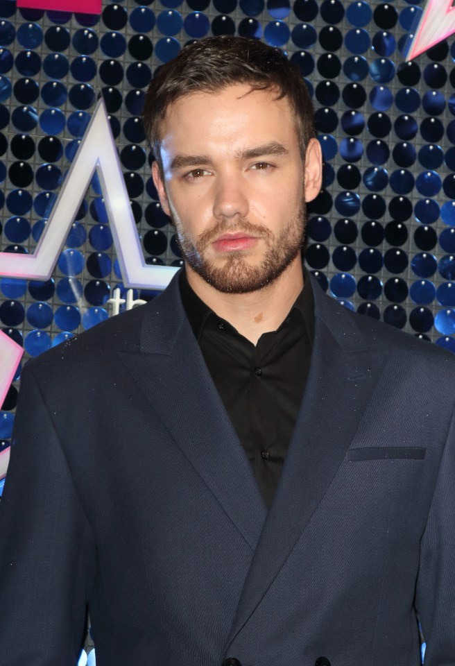 a man with a beard is wearing a blue suit and black shirt