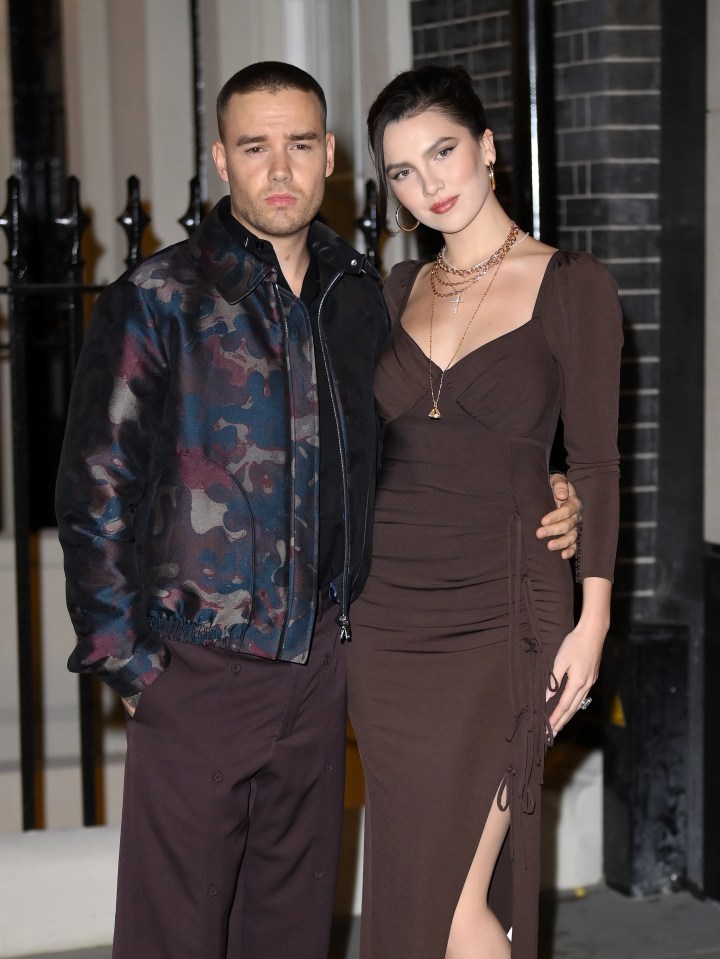 a man in a camouflage jacket stands next to a woman in a brown dress