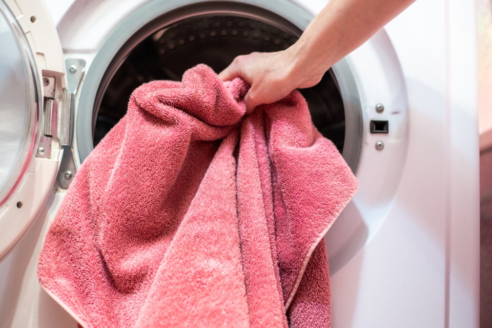 a person is pulling a pink towel out of a washing machine