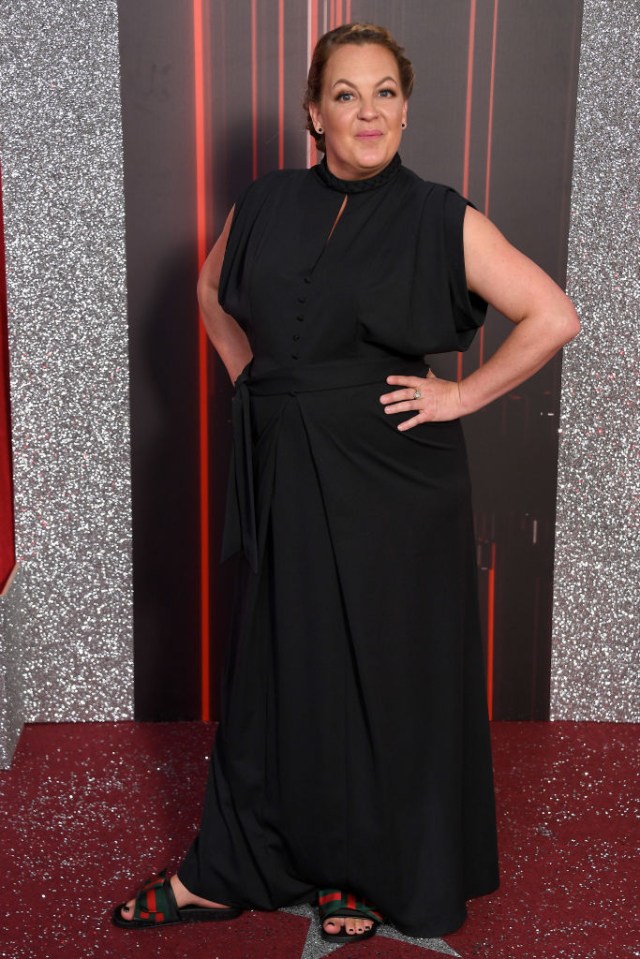 a woman in a black dress is standing on a red carpet