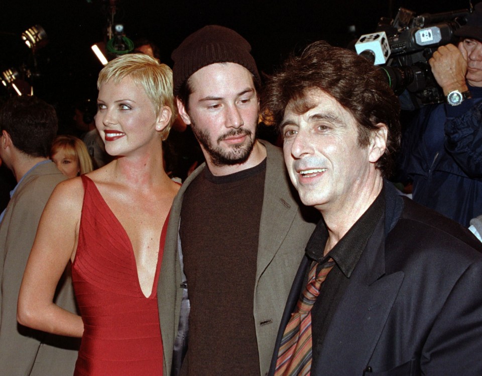 a man in a suit stands next to a woman in a red dress