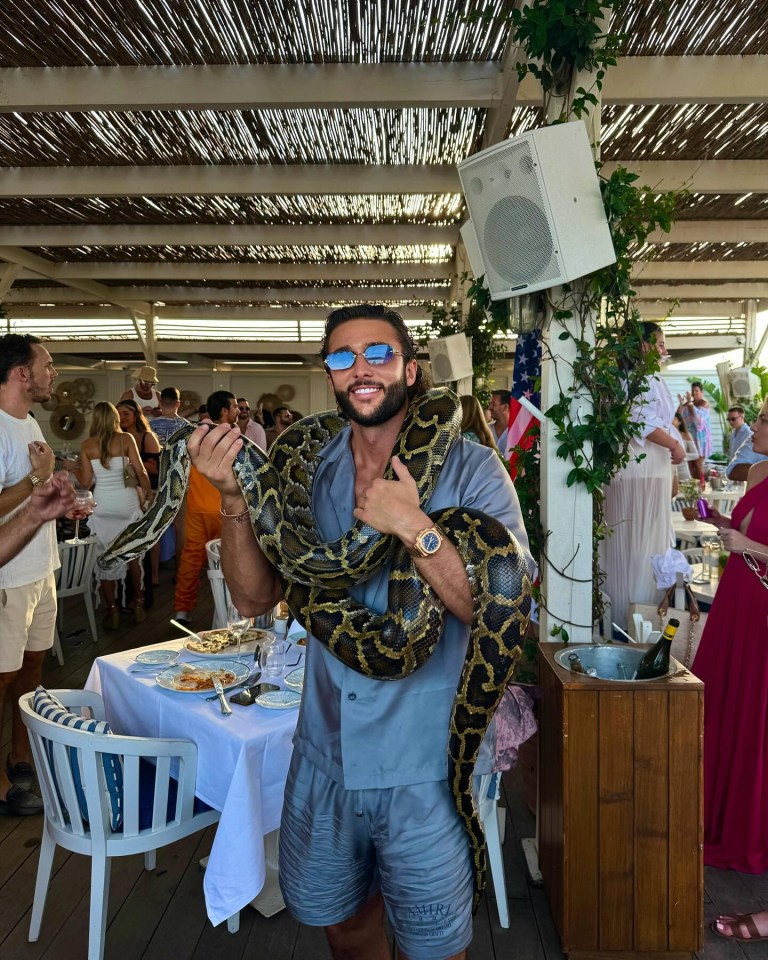 a man holding a large snake in a restaurant