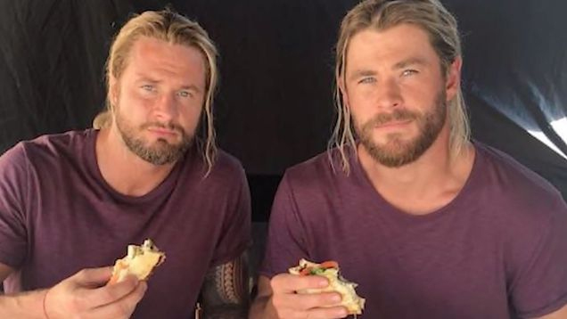 two men are sitting next to each other eating sandwiches .