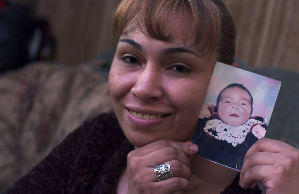 a woman with a ring on her finger is holding a picture of a baby