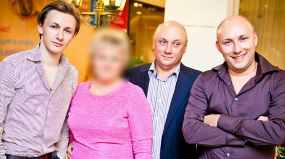 a man in a suit stands next to a woman in a pink shirt