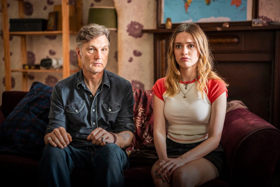 a man and a woman sit on a couch in front of a map of the world