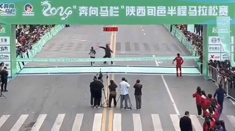 a runner crosses the finish line in front of a sign that says zong