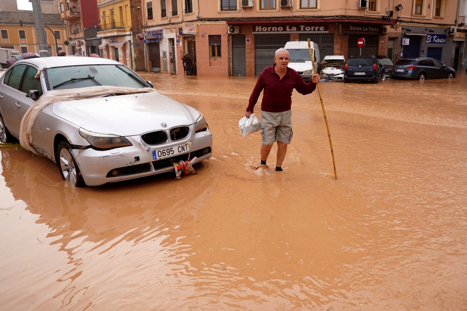 a man is walking through a flooded street near a store called horno la torre