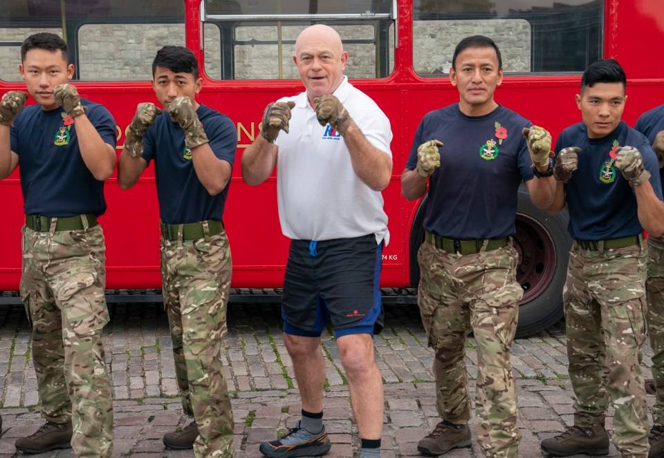 a group of soldiers are standing in front of a red bus