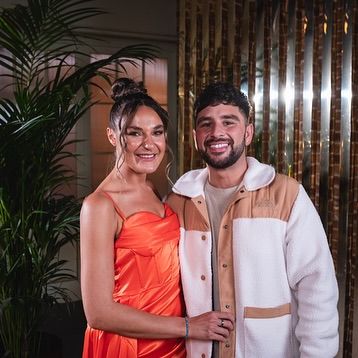 a man and a woman are posing for a picture in front of a palm tree .