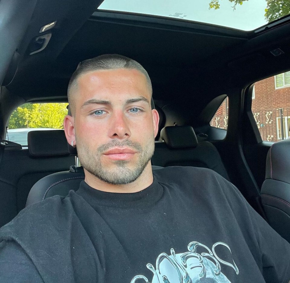 a man wearing a black shirt with a skull on it is sitting in a car