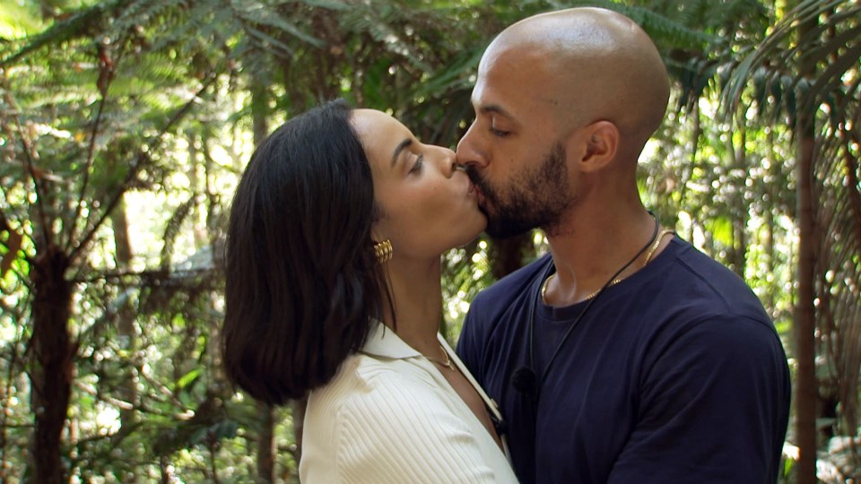 a man and a woman are kissing in the woods