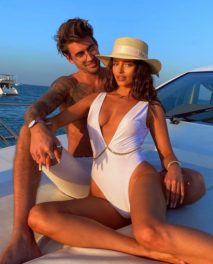 a man and a woman are sitting on a boat and the woman is wearing a white swimsuit