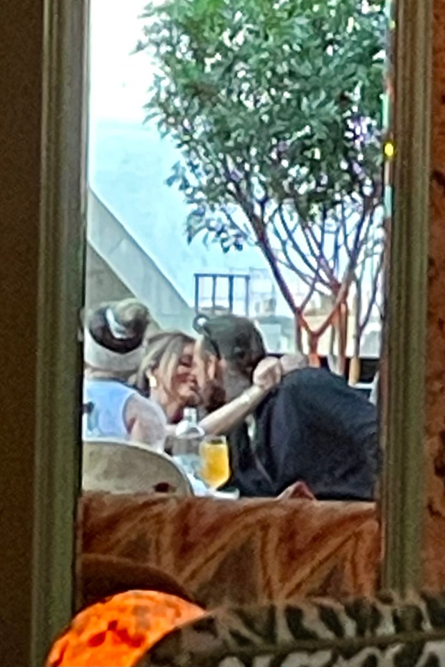 a man and woman kissing in front of a window