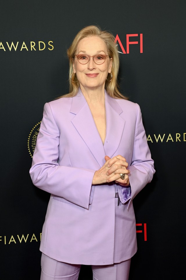 a woman in a purple suit stands in front of a sign that says awards