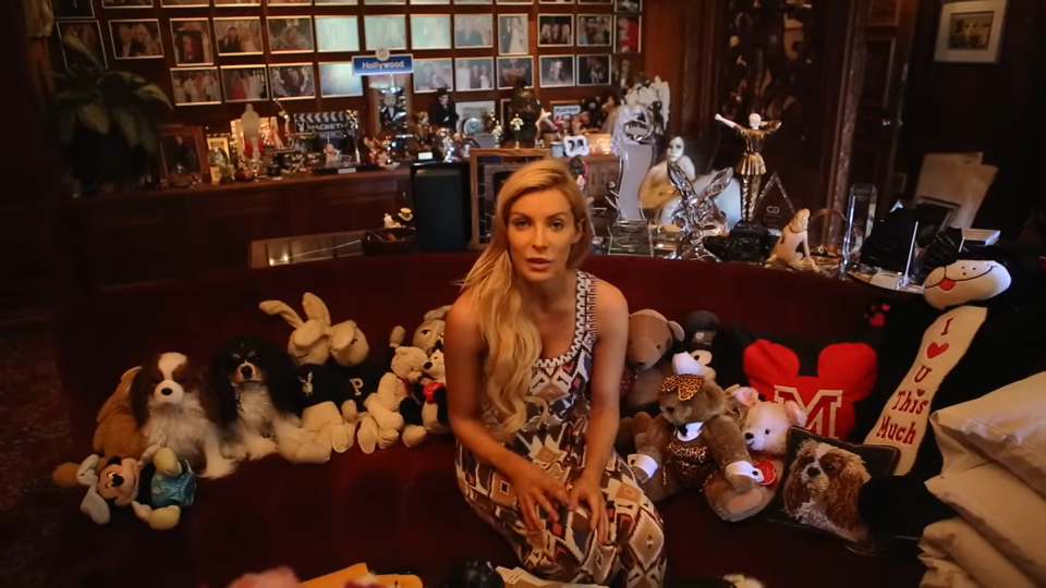 a woman sits on a couch surrounded by stuffed animals including a playboy dog