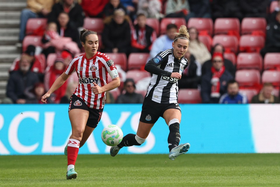 two female soccer players on a field with one wearing a nory jersey