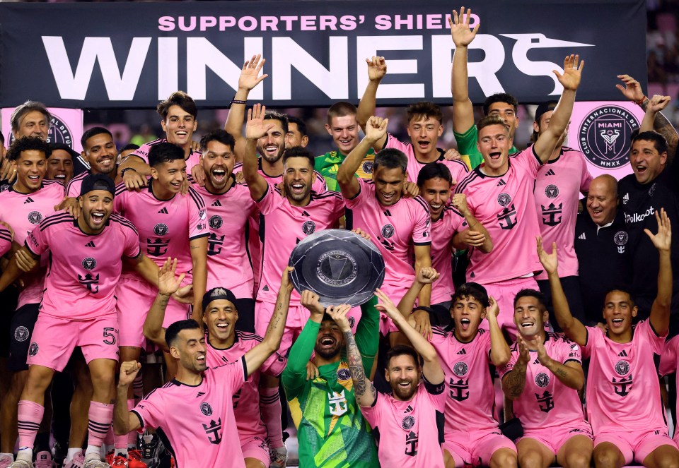 a group of soccer players holding a trophy in front of a banner that says supporters ' shield winners