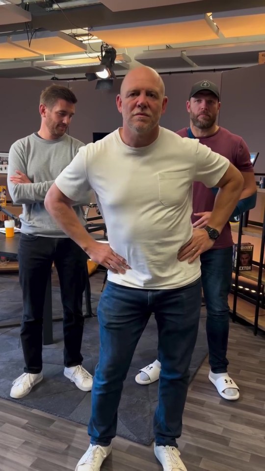 a man in a white t-shirt stands with his hands on his hips