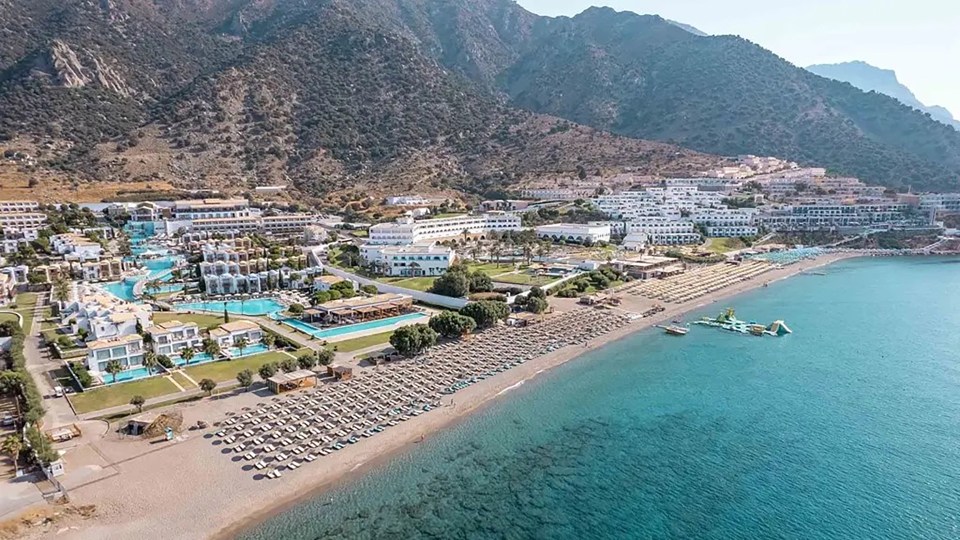 an aerial view of a beach resort with mountains in the background