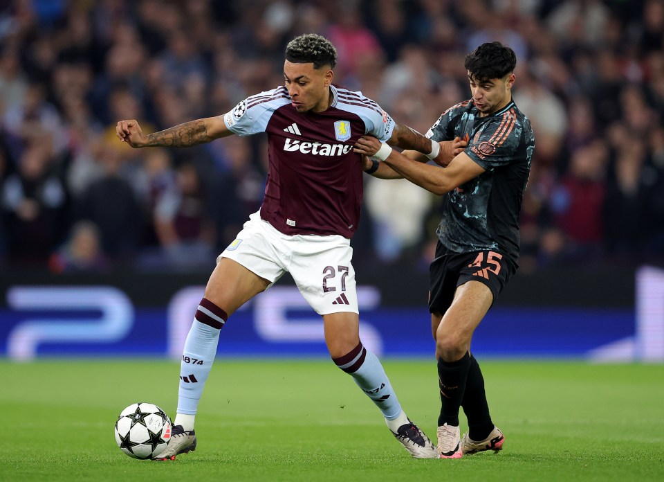 Aston Villa's Morgan Rogers challenged by a Bayern Munich player during a soccer match.