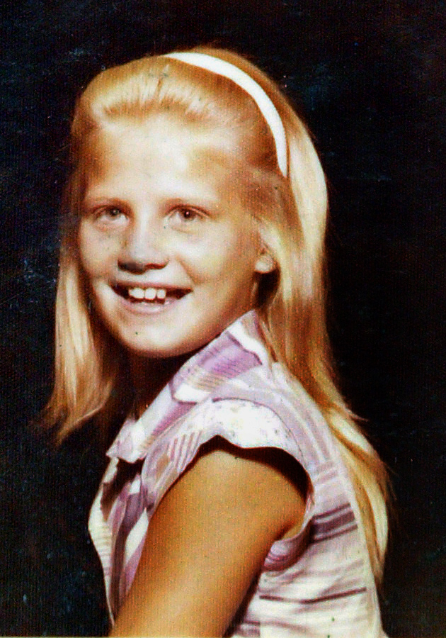 a young girl with blonde hair and a white headband smiles for the camera