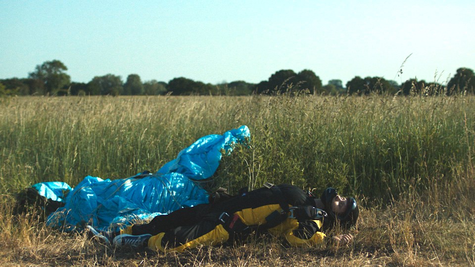 a person laying in a field with a blue parachute