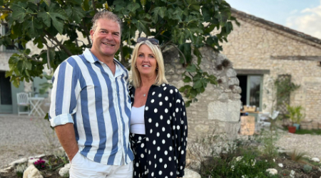 a man and woman standing in front of a stone building