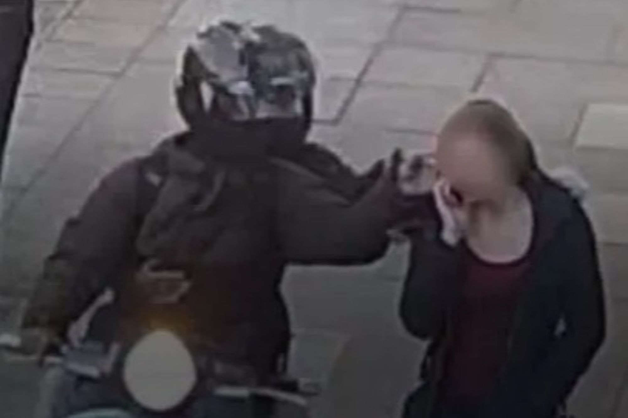 a man on a motorcycle is talking on a cell phone to a woman .