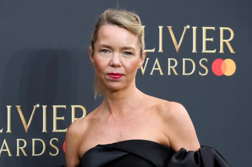 a woman stands in front of a sign that says olivier awards