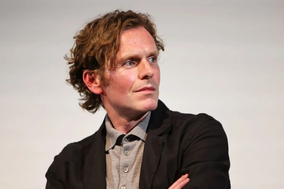 a man with curly hair is wearing a black jacket