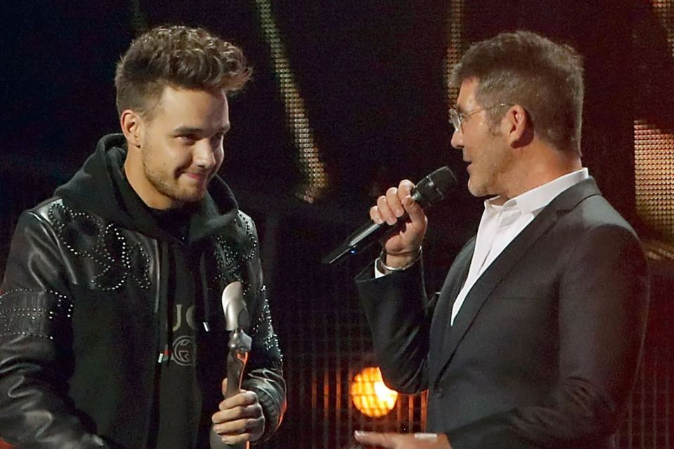 a man in a suit is holding a microphone and talking to another man