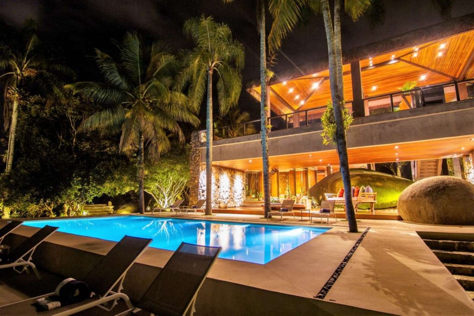 a large swimming pool is surrounded by chairs and palm trees