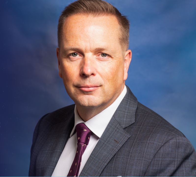 a man in a suit and tie stands in front of a blue background