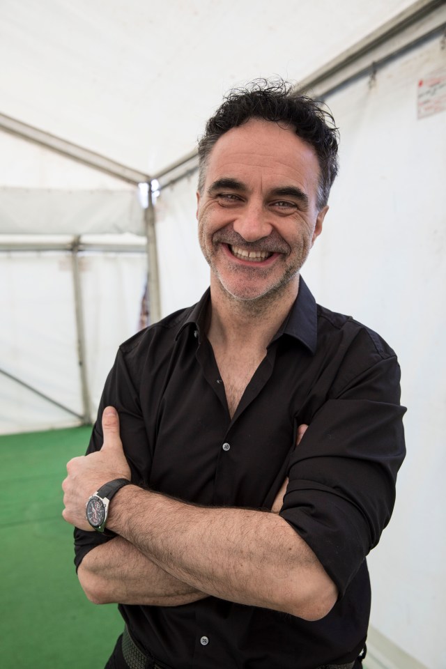 a man in a black shirt is smiling with his arms crossed