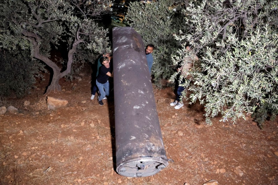 Palestinians pick up one exploded missile