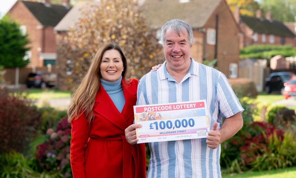 a man and woman holding a postcode lottery cheque