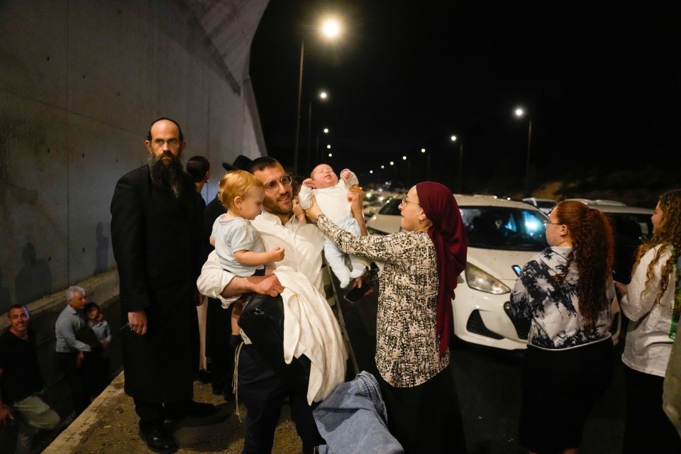 People take cover on the side of a road as sirens sound a warning of incoming rockets on a freeway towards Jerusalem