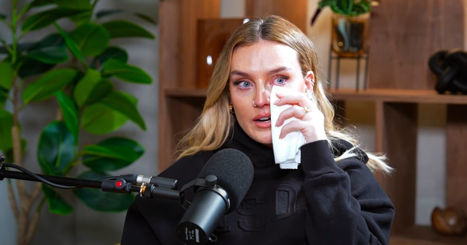 a woman wipes her eyes with a napkin in front of a microphone